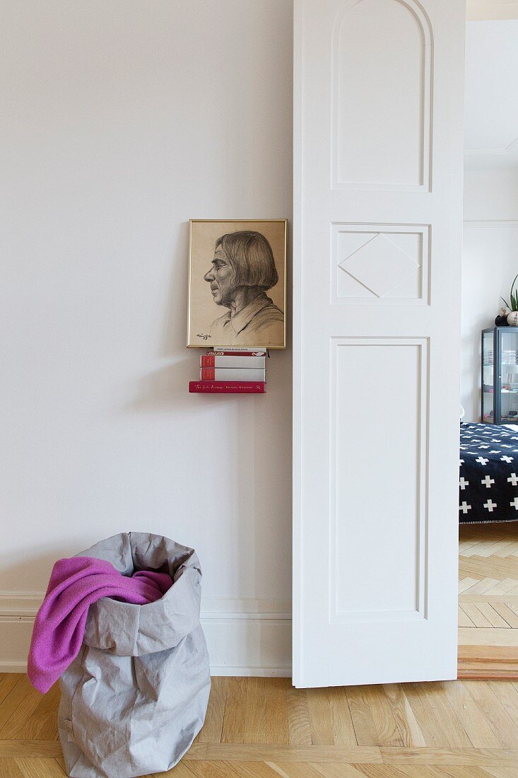 Blick vom Wohnraum mit Portraitbild und Sack auf die Flügeltür zum Schlafraum