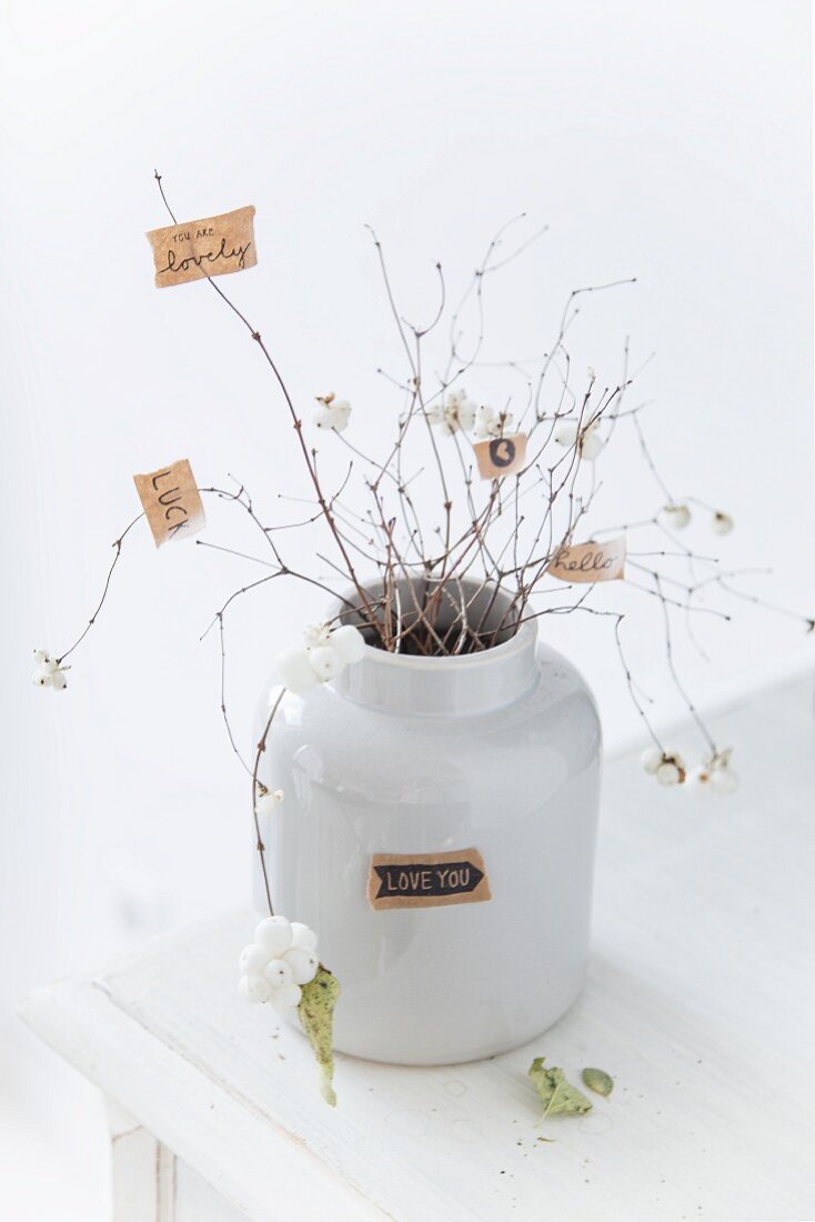 Schneebeeren Zweige mit angehefteten, kleinen Zetteln, in weißem Retro Keramik Behälter