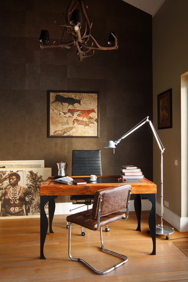 Retro-Freischwingerstuhl mit Lederbezug vor postmodernem Schreibtisch, seitlich Designer Stehleuchte vor bronzefarbener Wand