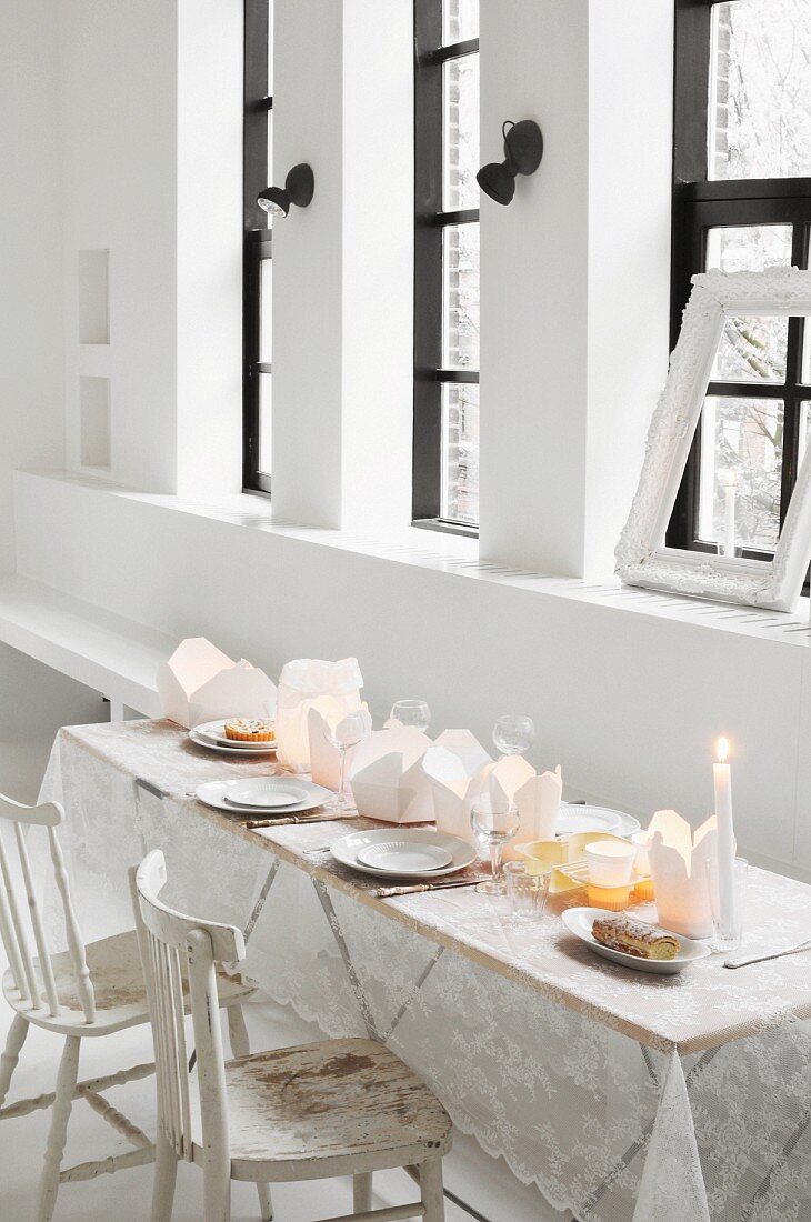 Table set with lace tablecloth and take-away cartons used as tealight holders in loft apartment