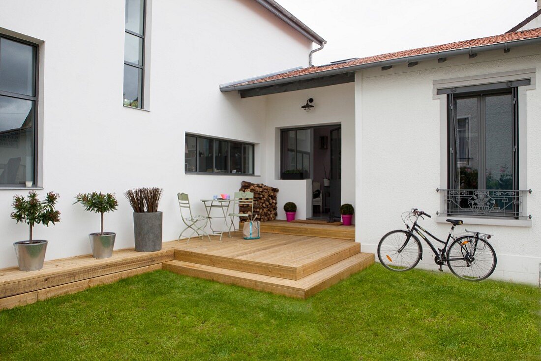 Modernes Wohnhaus mit rustikaler Holzterrasse, Rasen und Fahrrad