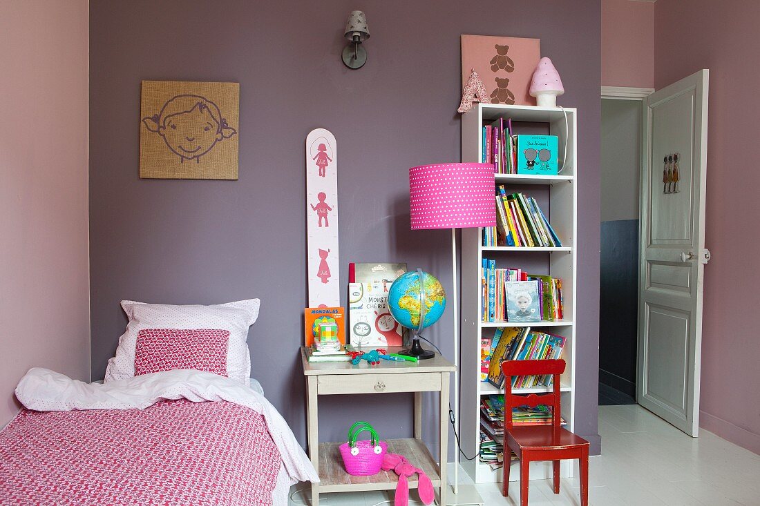 Mädchenzimmer mit mauvefarbenem Wandanstrich, offenem Regalschrank und pinkfarbener Stehleuchte
