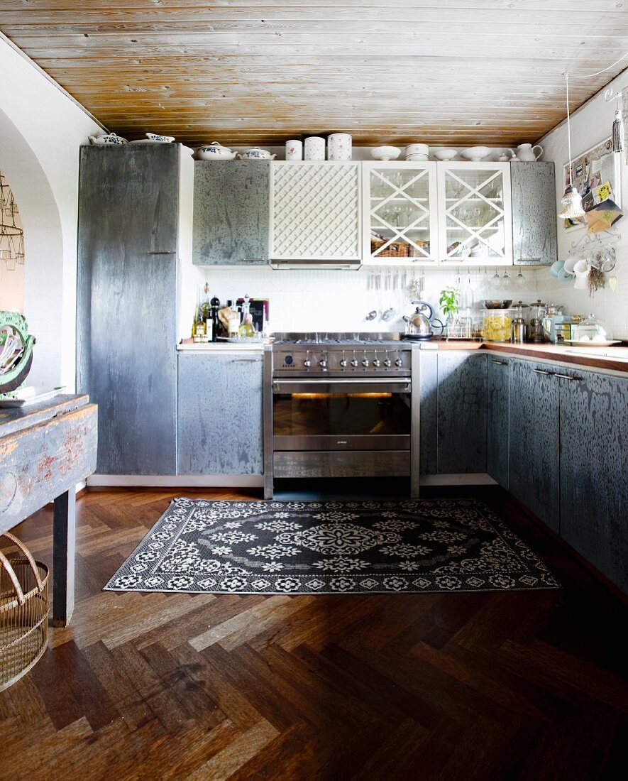 Einbauküche mit grauen Schrankoberflächen in schlichter Küche mit Vintage Teppich auf Fischgrätboden