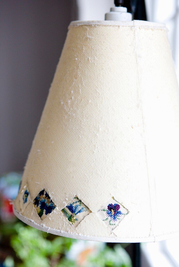 Lampenschirm aus hellem Stoff mit Stiefmütterchen- Muster verziert