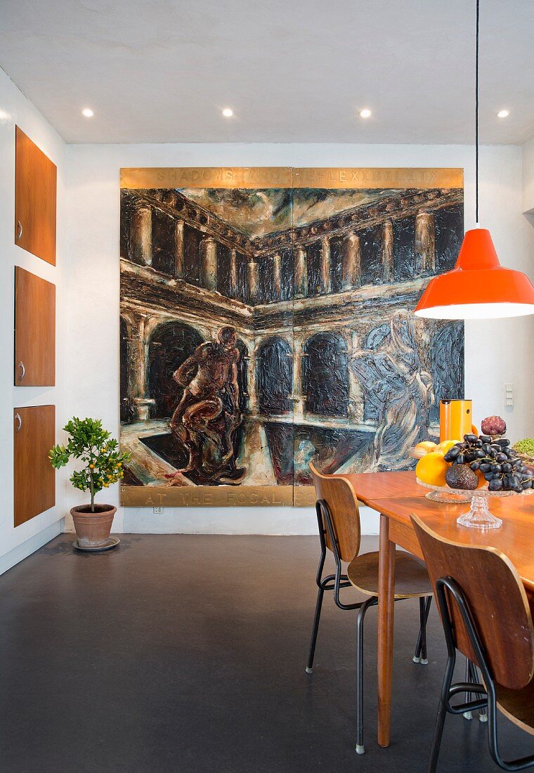 Large painting in dining area with extendible table, retro school chairs and orange pendant lamp