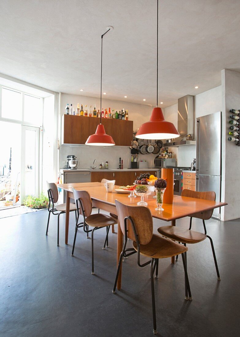 Retro kitchen with spacious dining area and orange pendant lamps in renovated town-house apartment