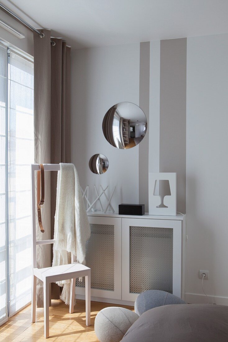 Convex mirrors above radiator cover in bedroom with valet stand