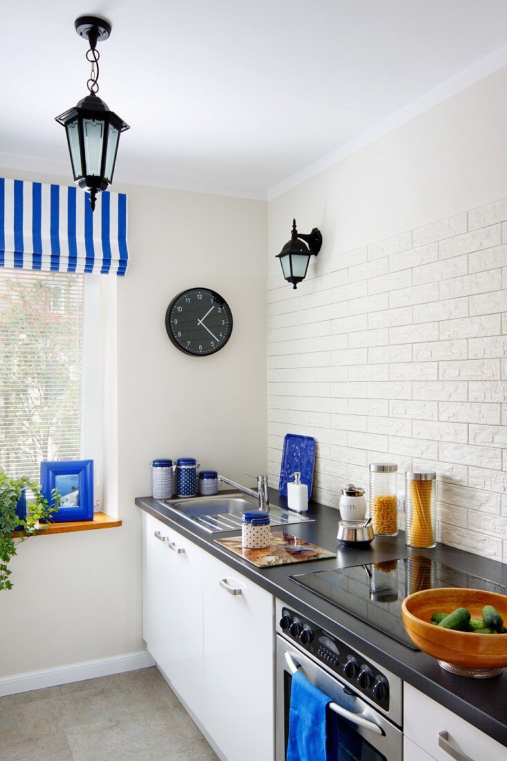 Moderne Küchenzeile mit weissen, strukturierten Riemchenfliesen als Spritzschutz, Farbakzente durch blaue Accessoires