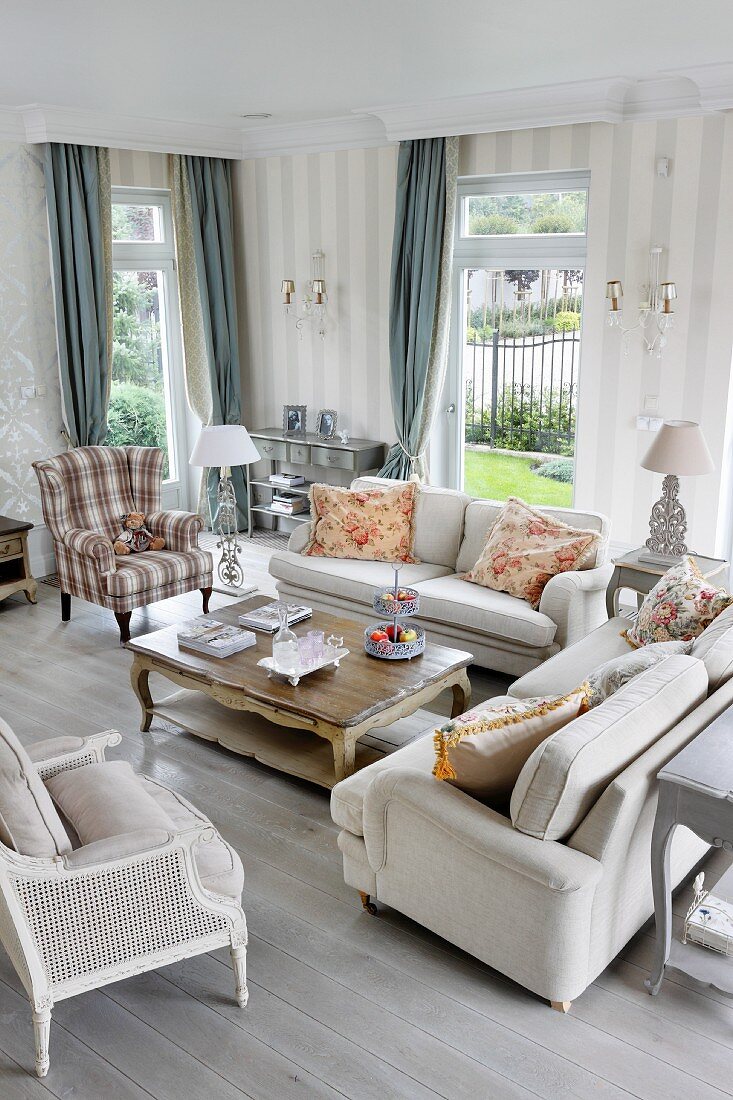 Pale, country-house-style sofas and armchairs in elegant interior with grey patterned wallpaper