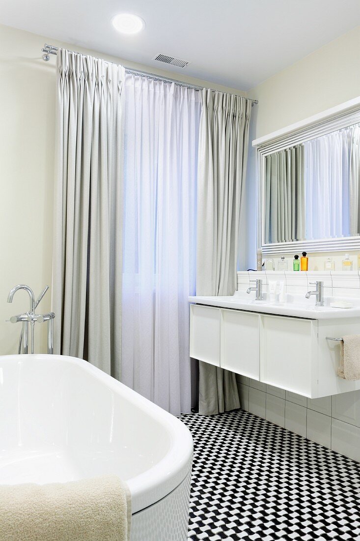 Bodenlange Vorhänge und schwarz-weisser Mosaikboden in elegantem Badezimmer