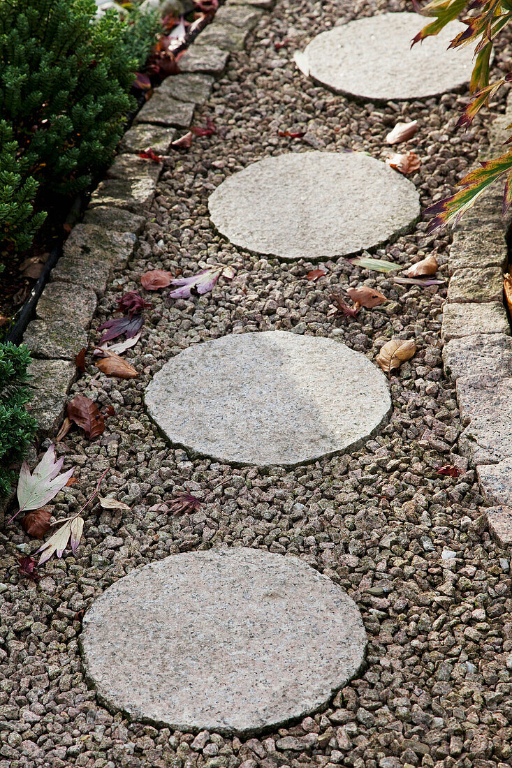 Runde Steinplatten auf gekiestem Gartenweg