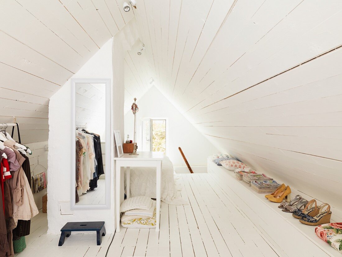 Ankleidebereich im Dachgeschoss mit weiß gestrichenem Dielenboden, Giebelfenster und Wandspiegel