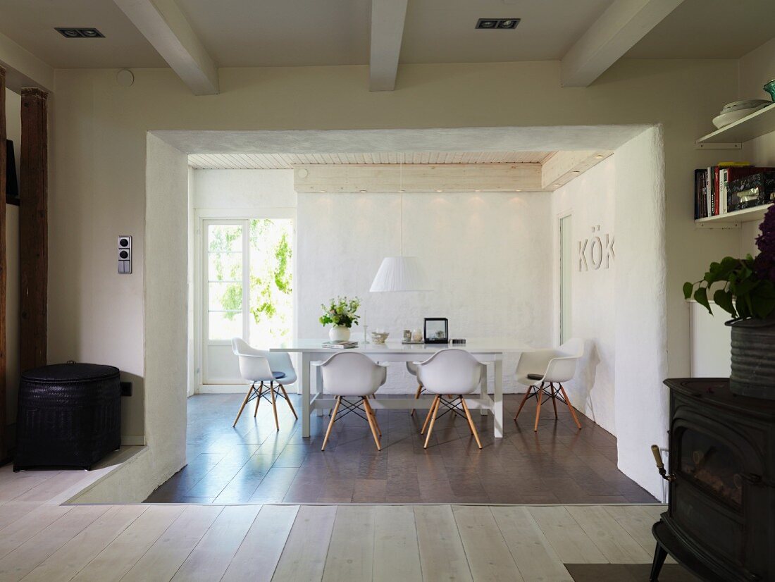 Abgesenkter Essbereich mit Fliesenboden und Designerstühlen vor geöffneter Terrassentür in renoviertem Landhaus