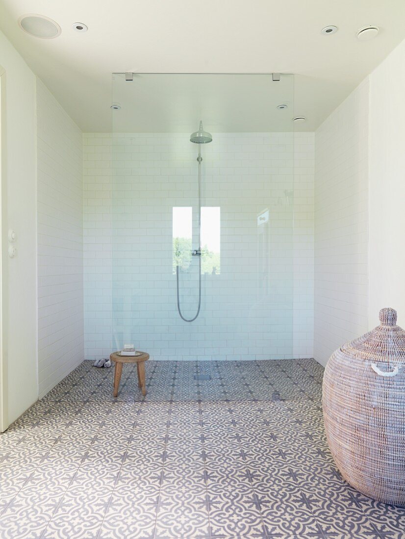 Geräumiger moderner Duschbereich mit Regendusche, Glasabtrennung und floral gemusterten Zementfliesen