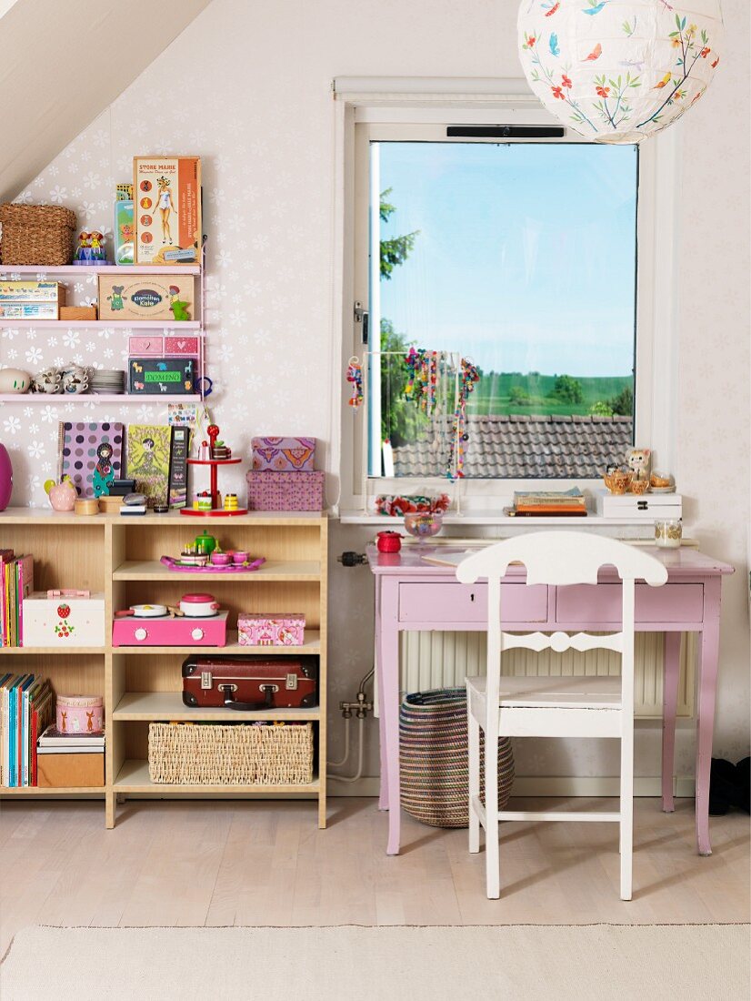 Mädchenzimmer mit rosafarbenem Schreibtisch, weißem Holzstuhl und offenem Spielzeugregal