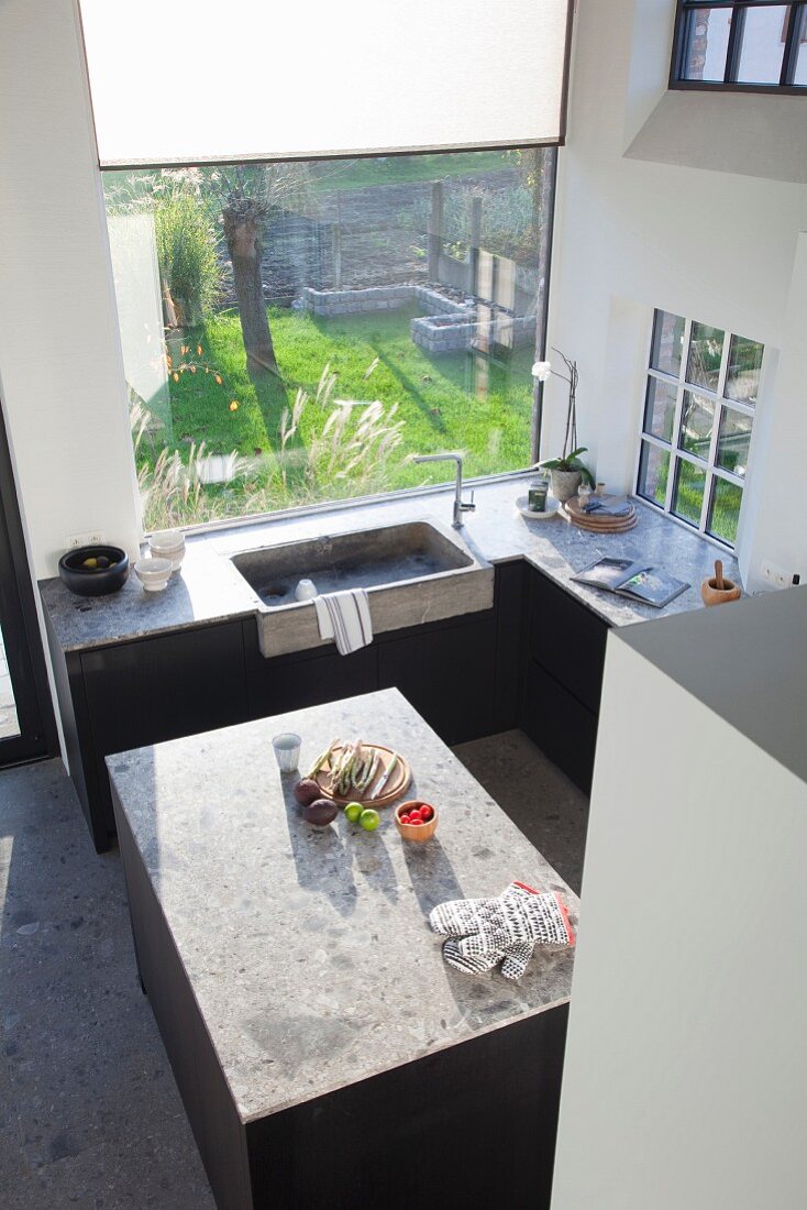 View down into purist fitted kitchen with free-standing island counter and integrated concrete sink below window