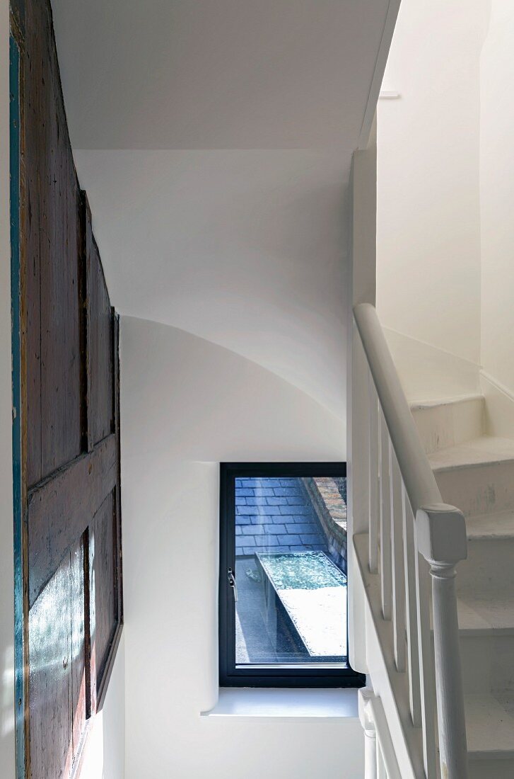 White stairwell with original wood-panelling on wall and winding staircase