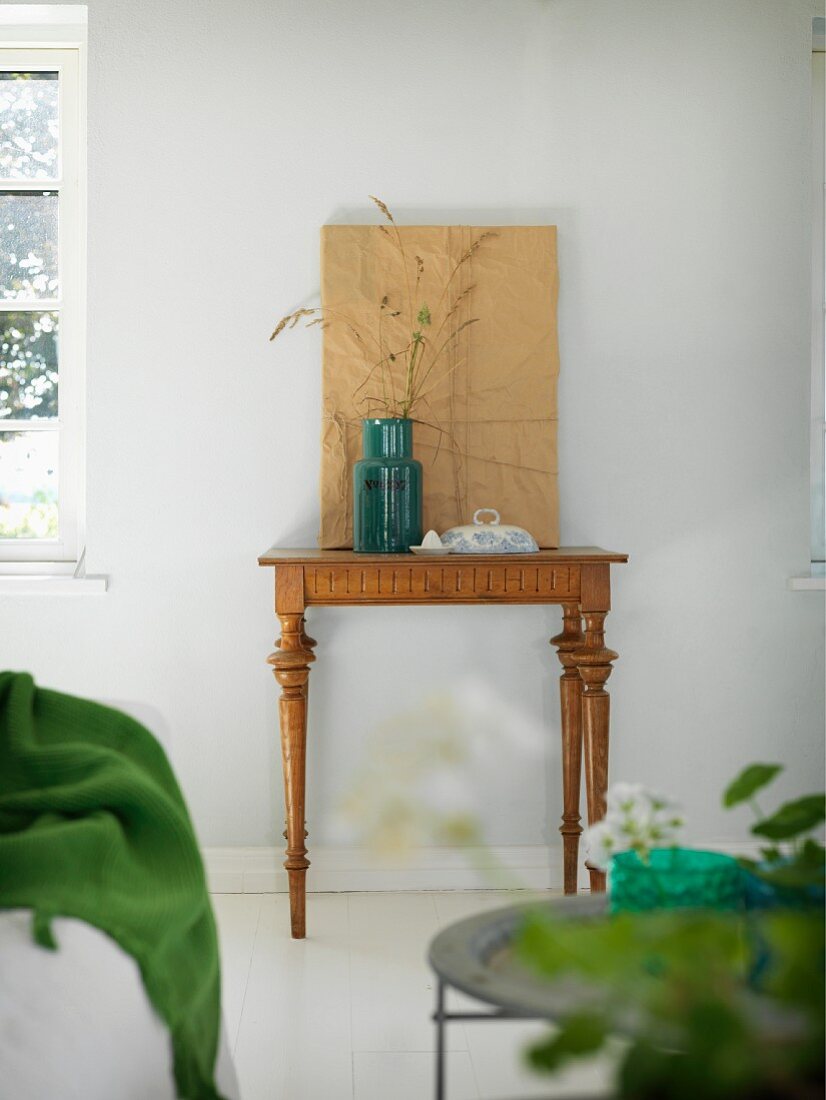 Retro Vase mit Ziergras auf antikem Wandtisch