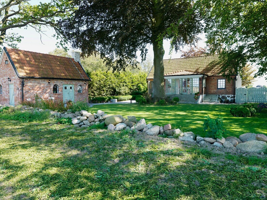 Boulders in garden with summer house and brick country house in background