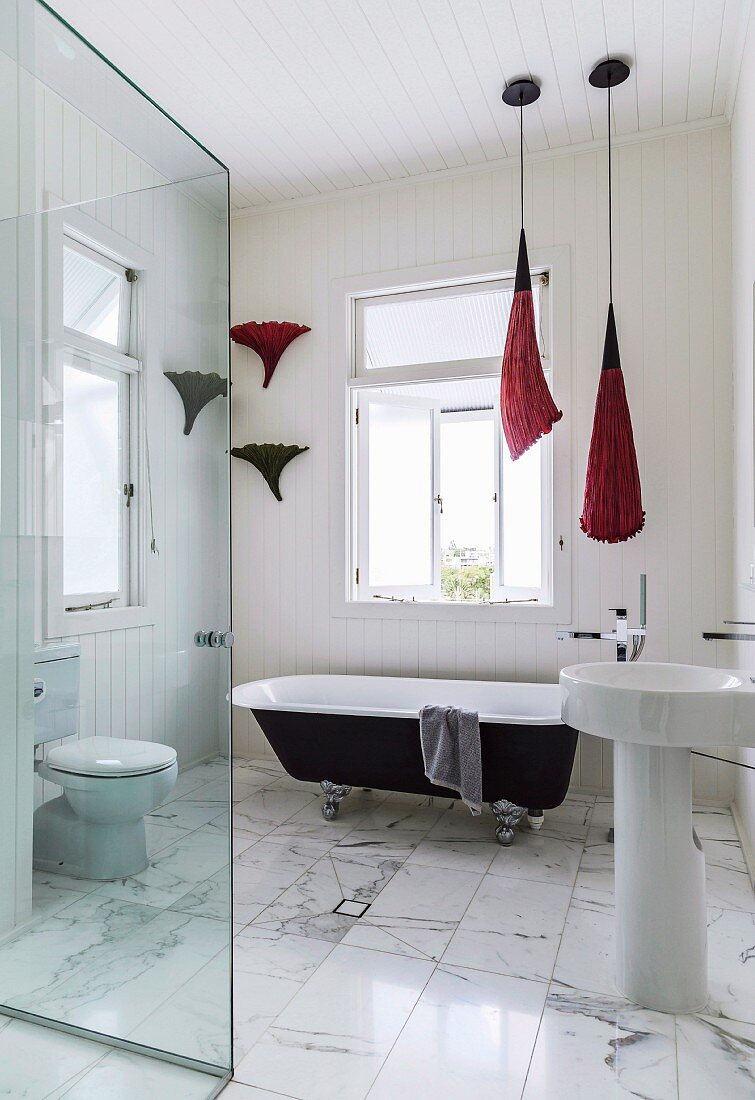 Modern, elegant bathroom with marble floor and vintage free-standing bathtub below window