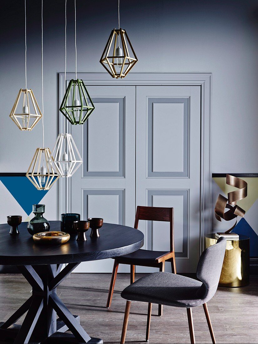 Pendant lamps with diamond-shaped wire lampshades above round table and retro chairs