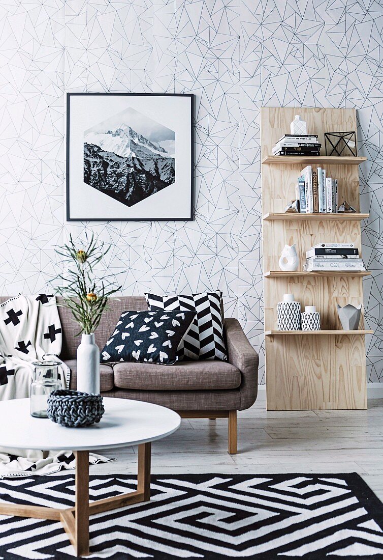 An die Wand gelehntes Regal, Sofa mit Kissen, Teppich mit schwarz-weißem Muster