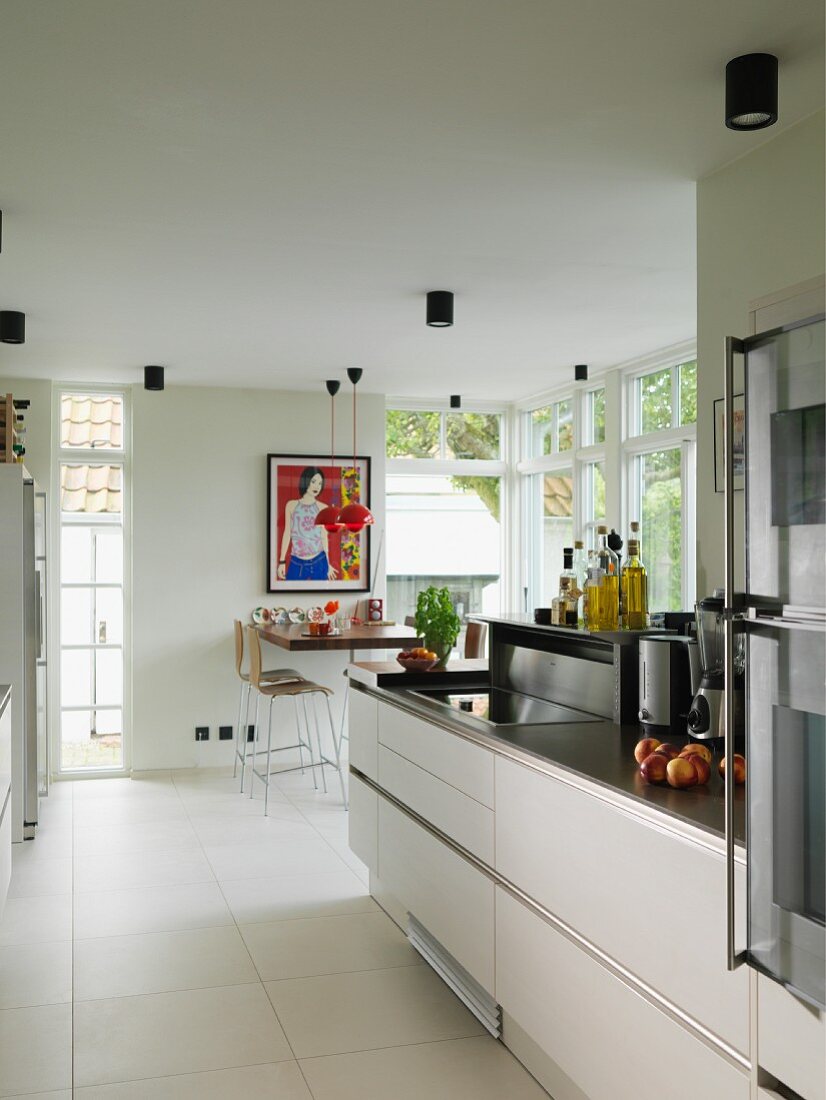 Offene Küche mit moderner Küchenzeile, im Hintergrund Essplatz zwischen Terrassentüren