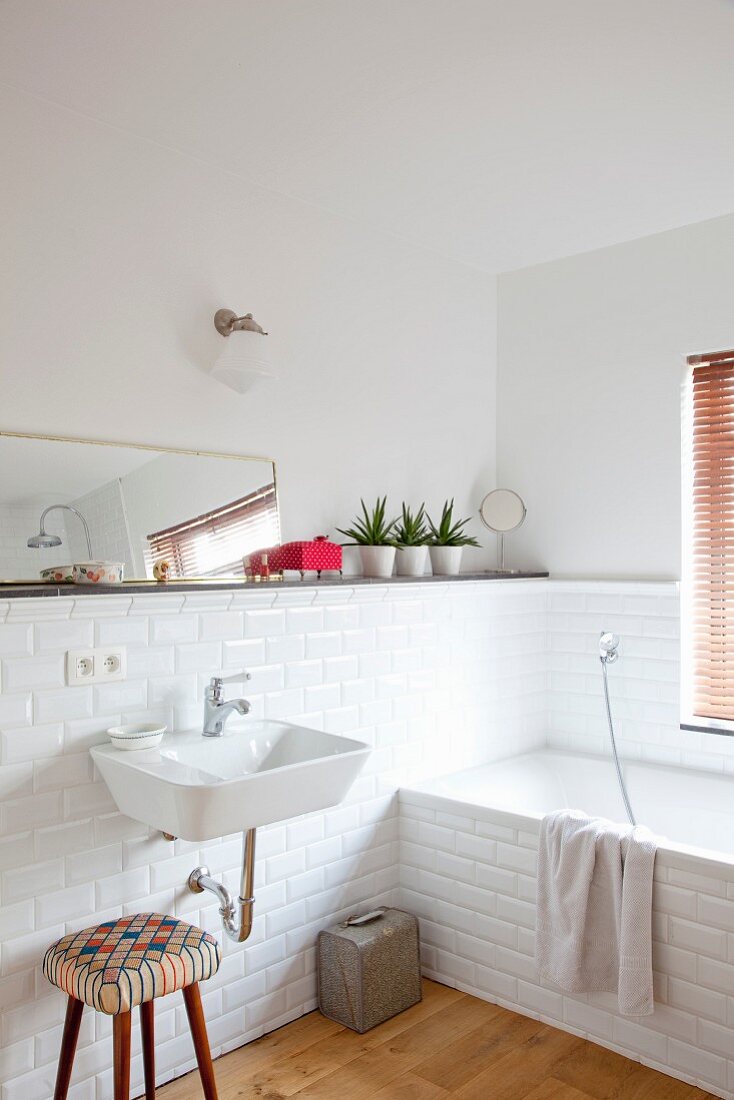 White subway tiles, stool and fifties-style sink in corner of bathroom