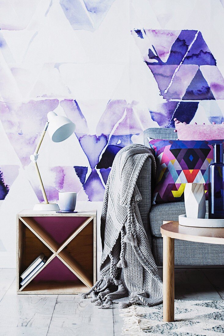 DIY Beistelltisch aus Holzkasten mit diagonalen Fächern, Dreiecksmotive auf Wand und Kissen