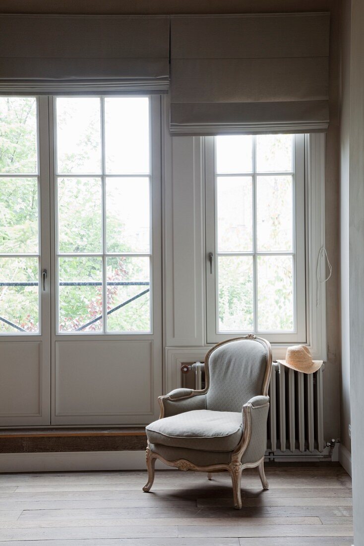 Rococo-style armchair below window in traditional interior