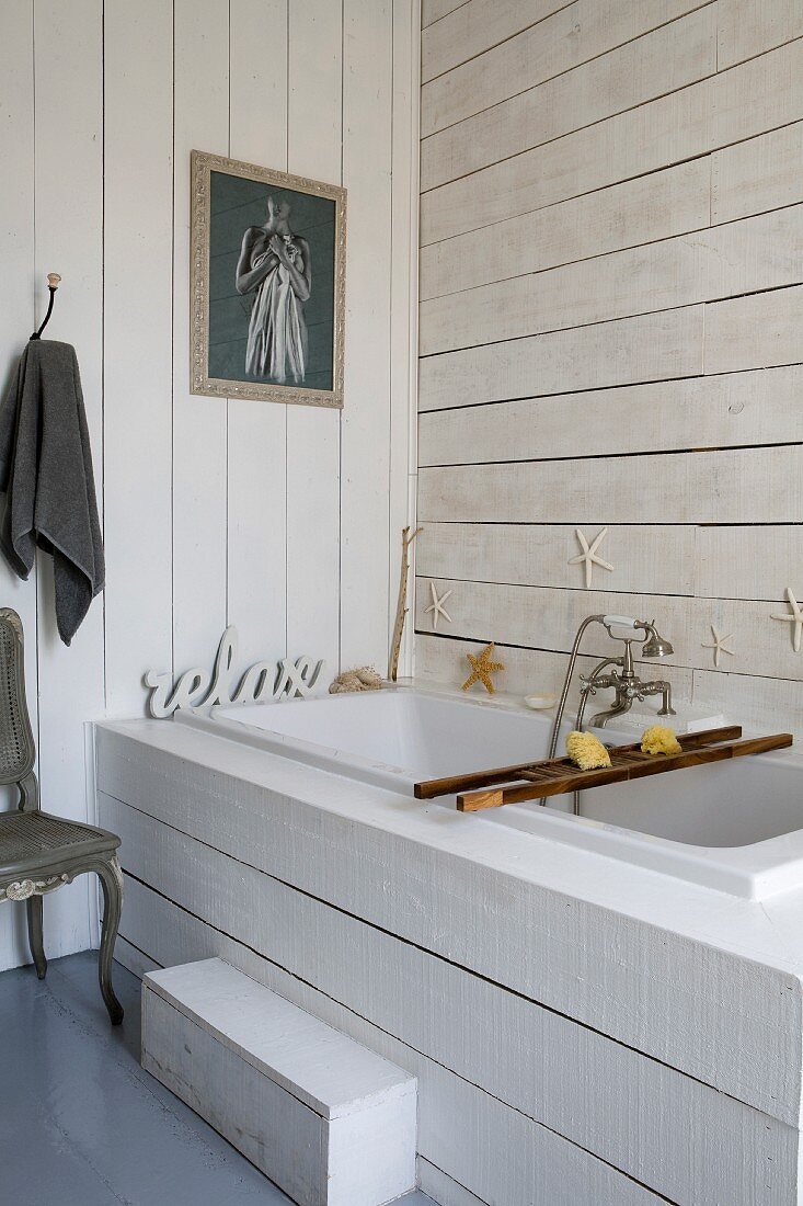 Built-in bathtub with white wood-clad surround and walls