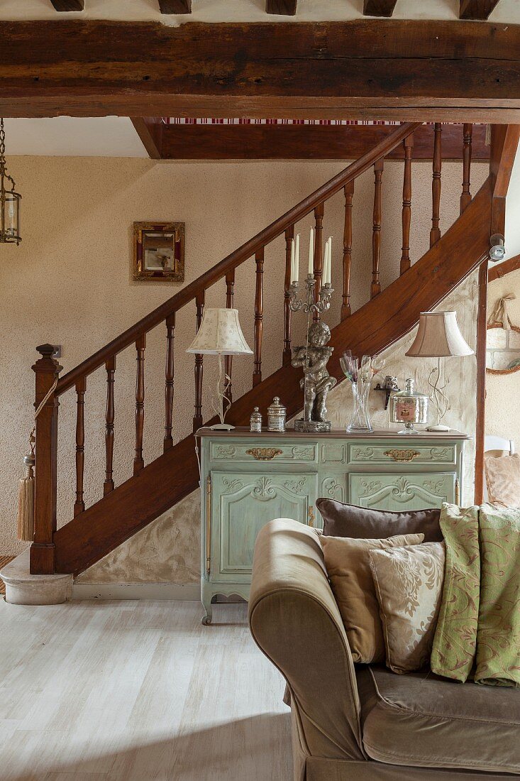 Turned staircase balustrade in open-plan, elegant, renovated interior with antique cabinet