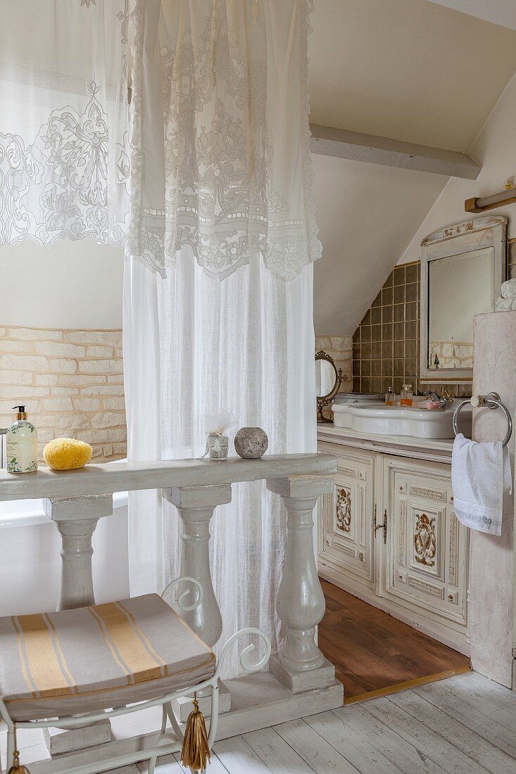 White curtains and wooden balustrade in antique ensuite bathroom