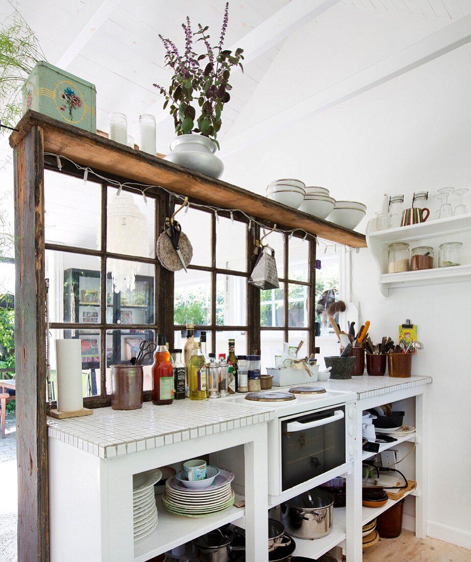 weiße Küchenzeile vor Raumteiler mit Sprossenverglasung in schlichtem Holzhaus