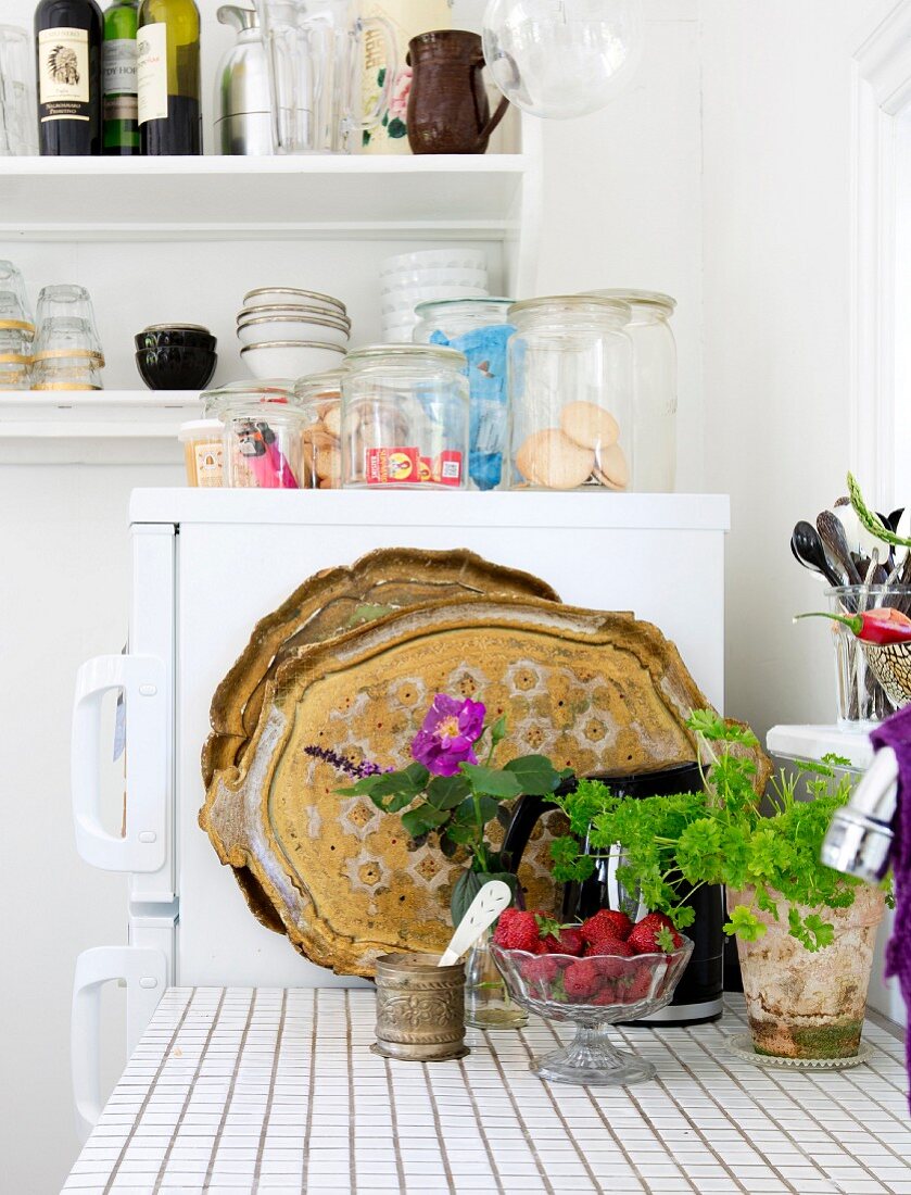 Ausschnitt einer Küchenzeile mit gefliester Arbeitsfläche, vor Kühlschrank mit Aufbewahrungsgläsern
