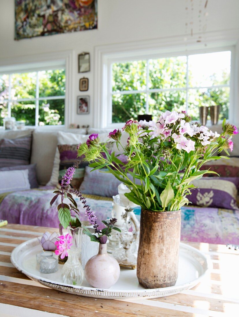 Gartenblumenstrauss und verschiedene Vasen mit Blumen auf Tablett