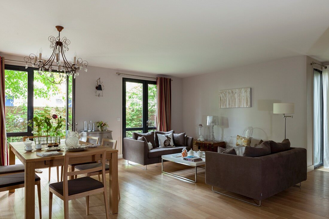 Offener, moderner Wohnraum mit Esstisch, im Hintergrund Loungeecke mit brauner Sofagarnitur