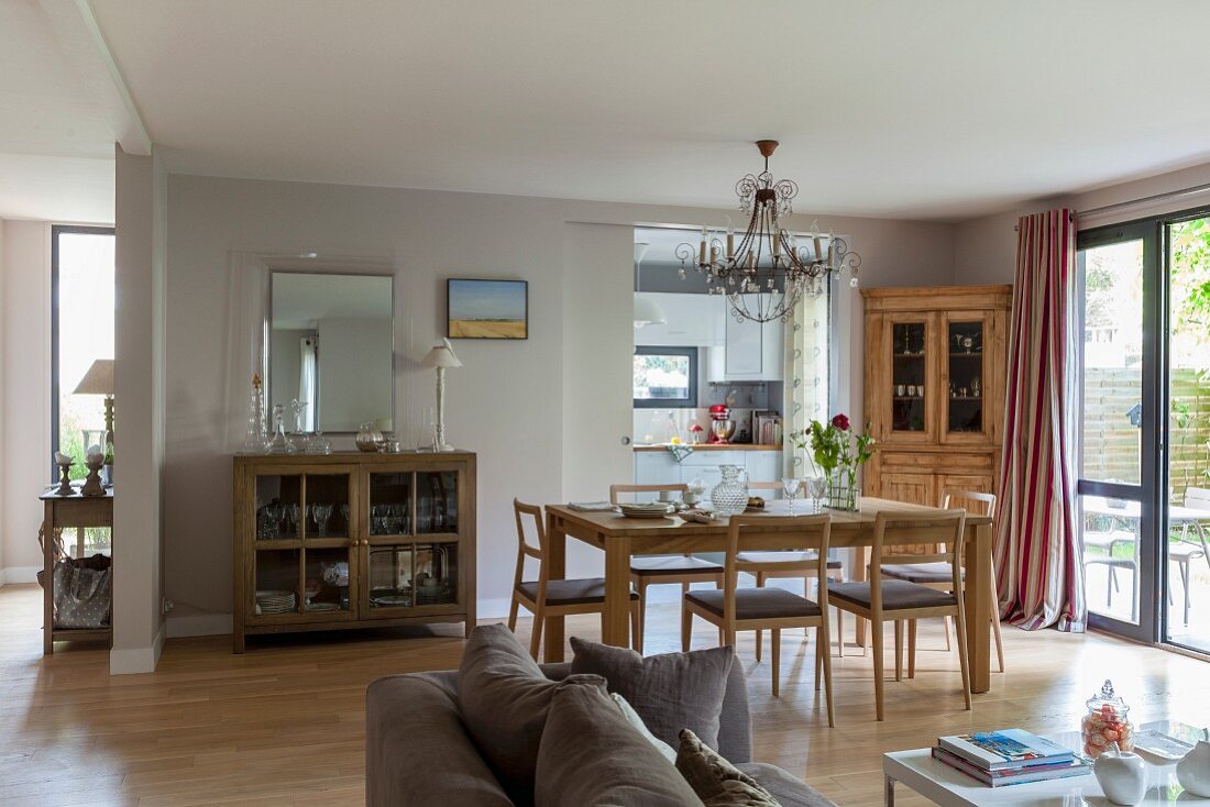 Offener Wohnraum mit Essplatz vor offener Schiebetür mit Blick in Küche, im Vordergrund teilweise sichtbares Sofa