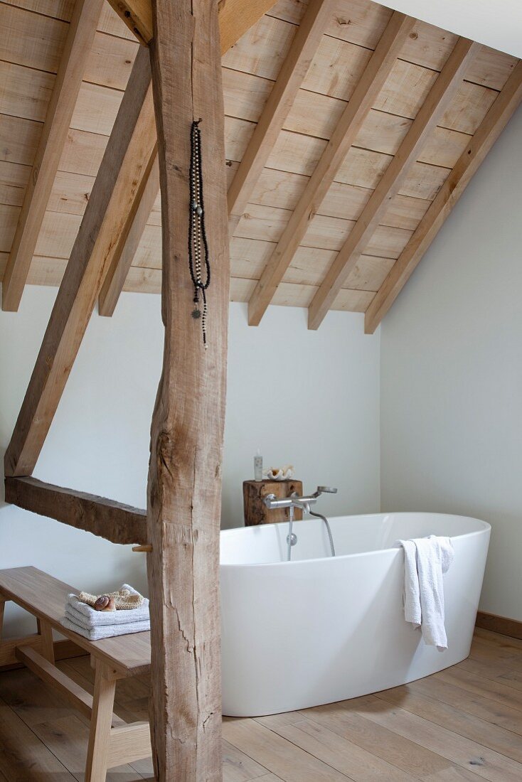 Free-standing white bathtub in rustic attic room