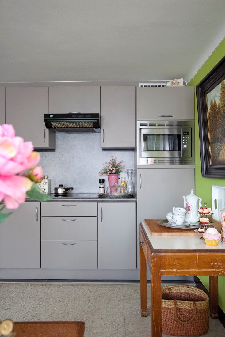 Modern fitted kitchen with grey fronts; crockery on long console table to one side
