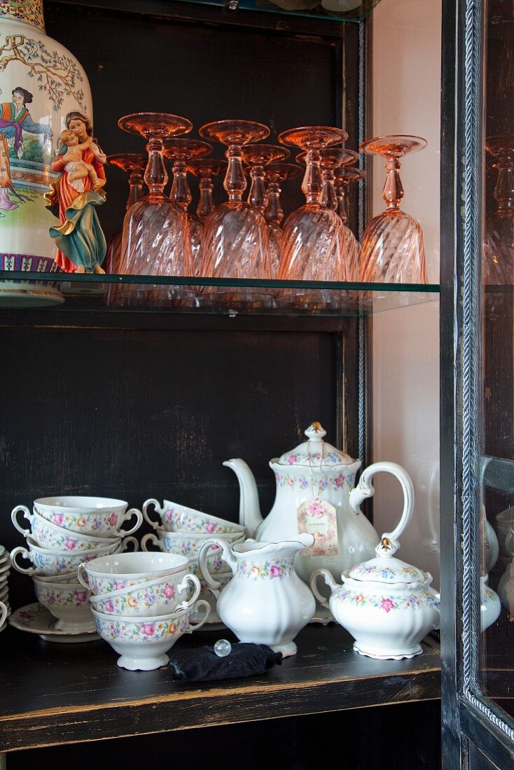 Open cupboard door showing traditional crockery with floral pattern