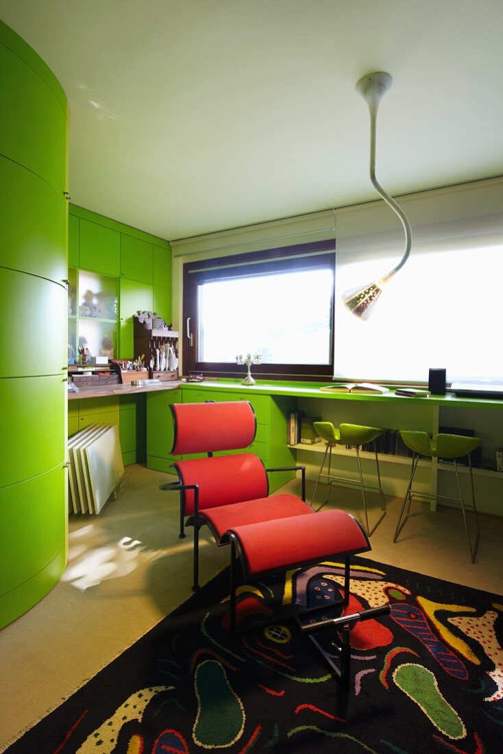 Rote Designerliege in Arbeitszimmer mit grünen Einbaumöbeln und schwarz gemustertem Teppich