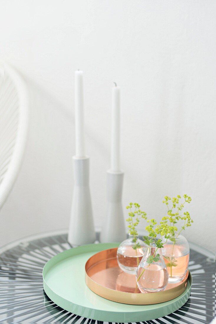 Vasen mit Blätterzweig auf Kupfer- und türkisfarbenem Tablett, weiße Keramik Kerzenhalter mit Kerzen