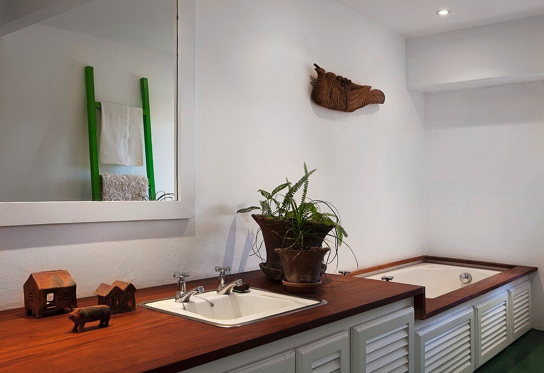 Washstand and bathtub integrated in base cabinets with slatted doors, exotic wood surfaces and ethnic ornaments