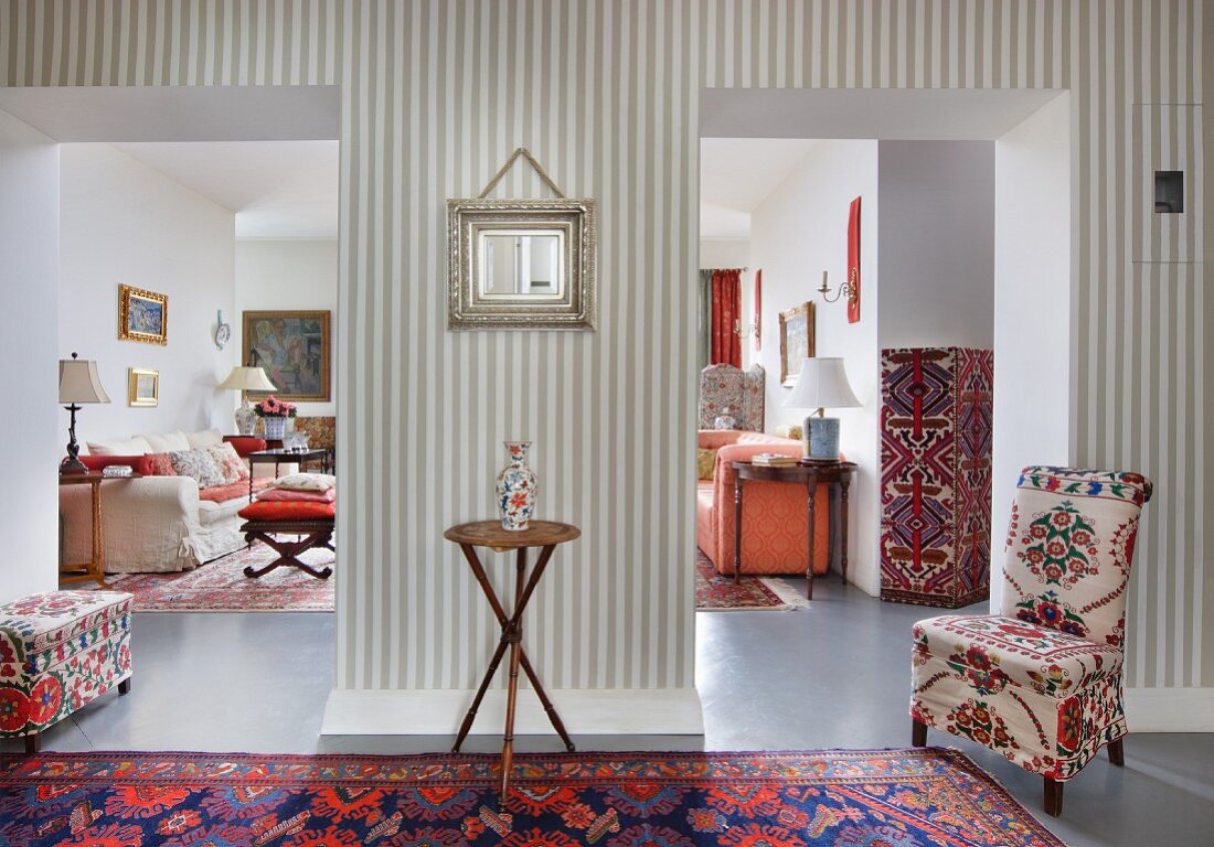 Wohnraum-Kontinuum eines Sammlers: Muster- und Stilmix mit Orientteppichen, bunten Polsterstoffen und grauweiss gestreifter Tapete
