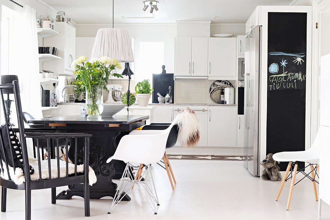 Dining area with black-painted table and classic shell chairs in open-plan fitted kitchen