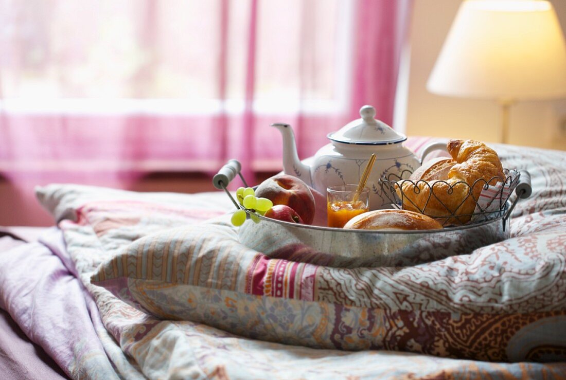 A breakfast tray on a cushion on a bed