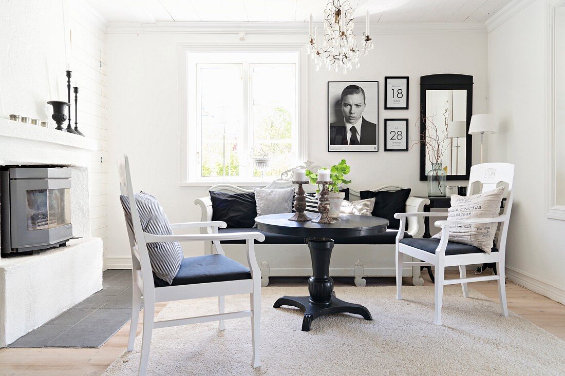 Schwarzer, runder Tisch und weiße Armlehnstühle in gemütlicher Wohnzimmerecke