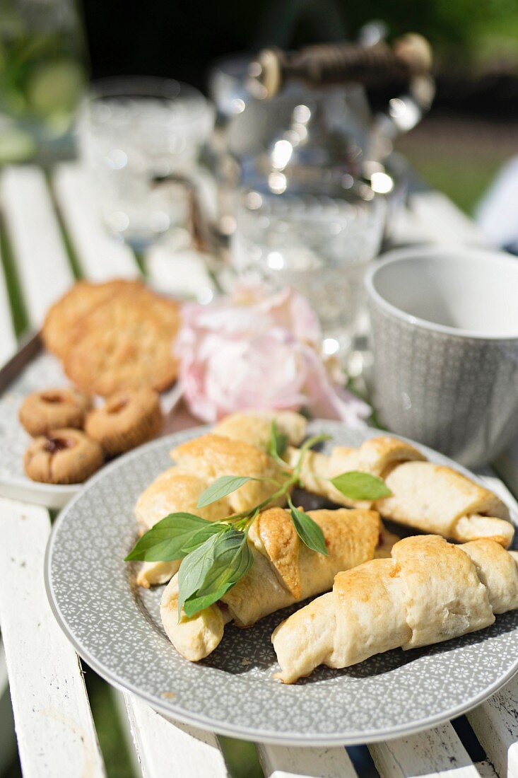 Home-made croissants and basil on garden table