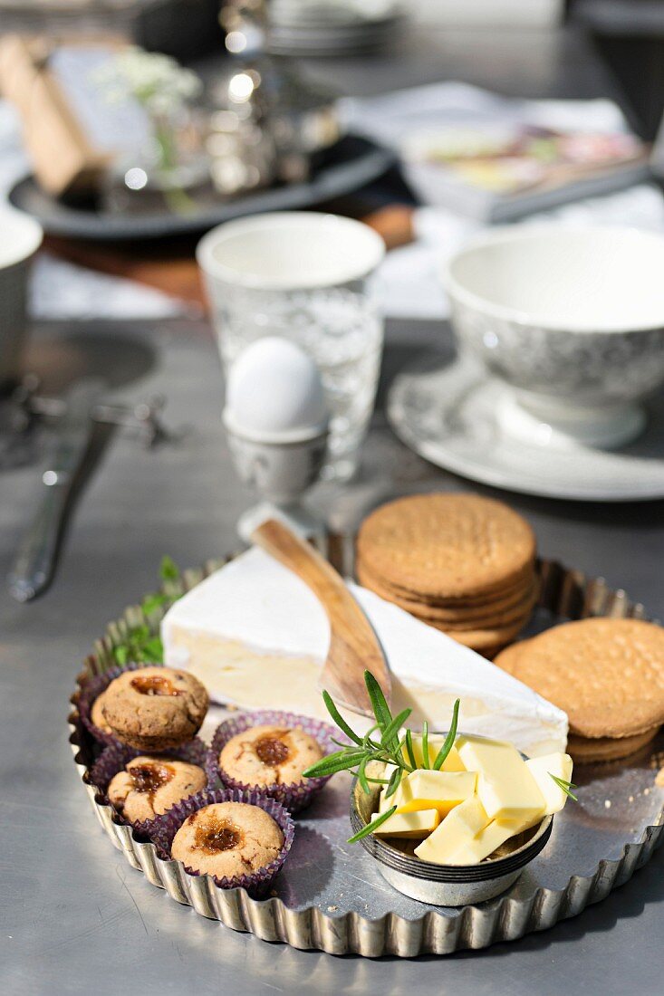 Himbeergebäck, Briekäse, Cracker und Butter in Kuchenform auf Frühstückstisch